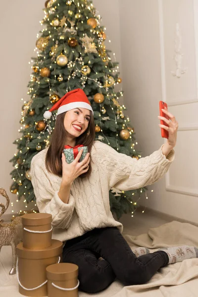 Молода дівчина телефонує батькам і показує зелену червону різдвяну коробку Ліцензійні Стокові Зображення