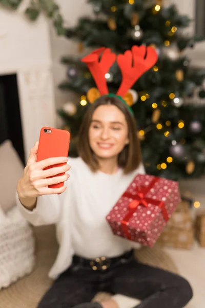 Close up mladé dívky telefon rodičům a ukázat červený vánoční dárek v ohnisku — Stock fotografie