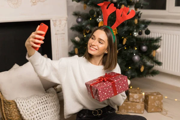 Вид збоку дзвінок молодої дівчини батькам і показати червоний різдвяний подарунок Ліцензійні Стокові Фото