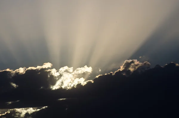 La luz del sol brillando a través de las nubes al ponerse el sol —  Fotos de Stock