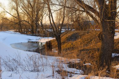 Ağaçlı bir vadide eriyen karla birlikte bahar akşamı manzarası