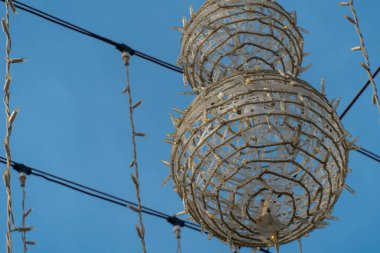 LED şeritleri açık hava dekorasyonlarını mavi gökyüzüne karşı top ve kurdele şeklinde şekillendirir.