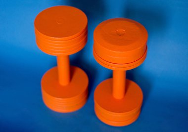 photo of two orange dumbbells blue background
