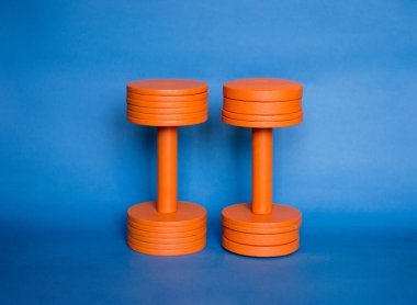 two orange dumbbells blue background photo