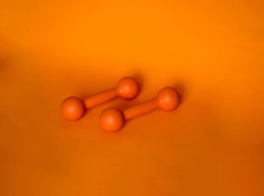 Two orange dumbbells on an orange background photo
