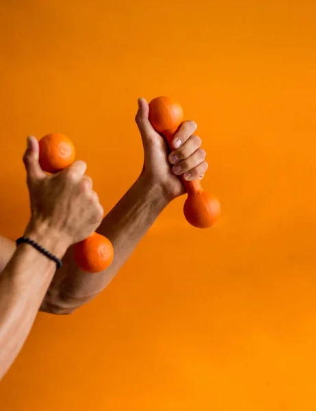 strong male hands holding orange dumbbells orange background photo