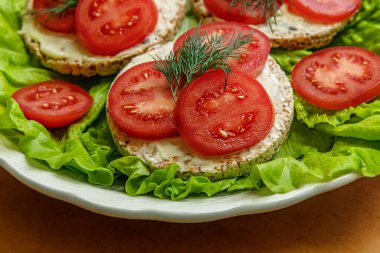 Krem peynirli diyet gevrekleri ve marul yapraklı domates dilimleri, sağlıklı yaşam tarzı konsepti.