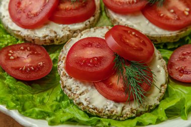 Krem peynirli diyet gevrekleri ve marul yapraklı domates dilimleri, sağlıklı yaşam tarzı konsepti.