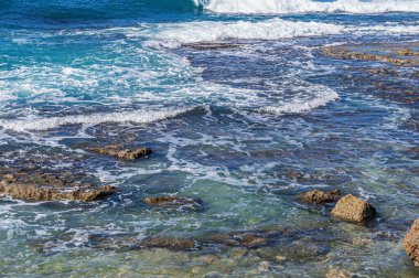 Açık rüzgarlı bir havada kayalık bir sahilde deniz sörfünün soyut arka planı