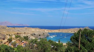 Lindos Sahili panorama manzarası turkuaz berrak su botu turistleri ve Rodos Yunanistan 'da güneş görüyor.