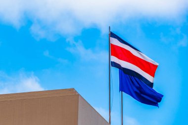 Kosta Rika bayrağı. Kosta Rika 'nın arkasında eski binalar var. San Jose Kosta Rika' da yetişmiş mavi bir bayrak..