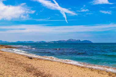 İspanya 'nın Mallorca adasındaki Can Picafort adasında turkuaz su dalgaları, kayalar ve taşlar ile pürüzlü doğal kıyı ve sahil manzarası.