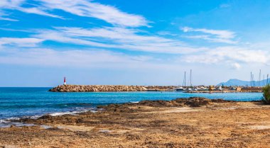 İspanya 'nın Mallorca adasındaki Can Picafort adasında turkuaz su dalgaları, kayalar ve taşlar ile pürüzlü doğal kıyı ve sahil manzarası.