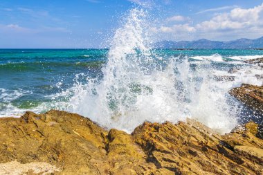 İspanya 'nın Balearic Adası Mallorca' daki Can Picafort 'ta, turkuaz su dalgaları, kayalar ve taşlar içeren sert doğal kıyı ve sahil manzarasında dev dalgalar..