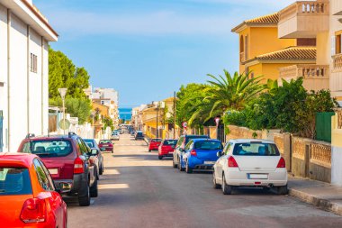 Palmiye ağaçları olan tipik sokak yolu İspanya 'nın Balearic Adası Mallorca' daki Can Picafort 'ta oteller binalar ve evler.