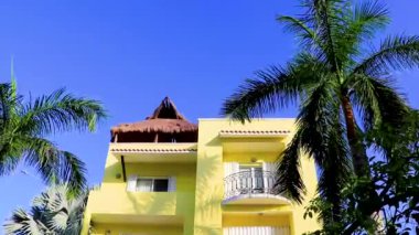 Playa del Carmen Meksika 'da palmiye ağaçları olan tipik sarı konutlu otel binası..