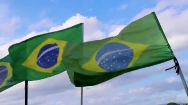 Brazilian flags waving in the wind with blue sky in the background in Rio de Janeiro Brazil in the colors green blue and yellow.