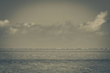 Feribottan, mavi bulutlu gökyüzü ve Quintana Roo Mexico 'daki turkuaz yeşil su ile güzel Holbox adasına uzanan manzaranın siyah ve beyaz bir resmi..