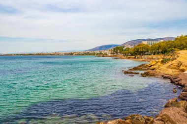 Yunanistan 'ın Voula kenti yakınlarındaki Vouliagmeni Sahili' nde doğal yeşil turkuaz plajı ve su.