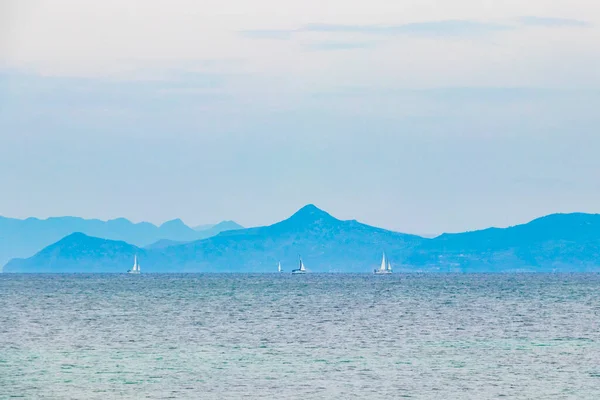 希腊Voula附近Vouliagmeni海滩的天然绿色绿松石海滩和配有帆船和山脉的水 — 图库照片