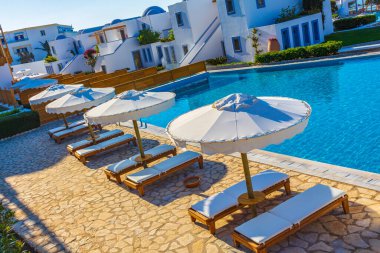 Doğal kıyı manzaralarında güneş pansiyonları ve şemsiyeli lüks tatil beldeleri ve plajlar Kos Adası Yunanistan 'da mavi gökyüzü.
