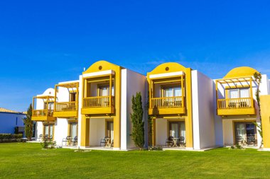 Doğal kıyı manzaralarında güneş pansiyonları ve şemsiyeli lüks tatil beldeleri ve plajlar Kos Adası Yunanistan 'da mavi gökyüzü.