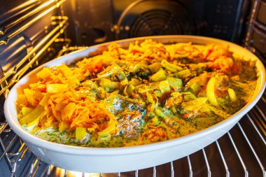 Gratins balıkları soğan, havuç makarna, makarna ve diğer yemekleri fırına koyar..