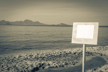 Yunanistan 'ın Kos Adası' ndaki güzel plajda, tepeler ve adalar manzaralı boş bir bilgi tahtası tabelasının eski siyah beyaz resmi..