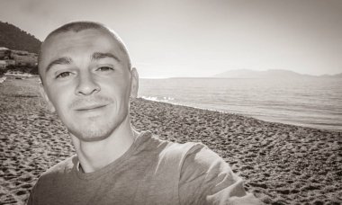 Yunanistan 'ın Kos Adası' ndaki doğal kıyı manzaralı, uçurumlu, turkuaz mavi plajlı ve dalgalı genç bir gezginin eski siyah beyaz resmi..