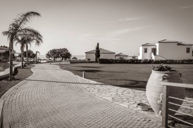 Yunanistan 'ın mavi gökyüzüne sahip doğal kıyı manzaralarında güneş pansiyonları ve şemsiyeli lüks tatil beldeleri ve plajların eski siyah beyaz resmi.