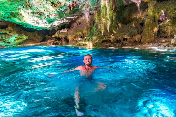 Traveler and tourist guide at amazing blue turquoise water and limestone cave sinkhole cenote Tajma ha Tajmaha in Puerto Aventuras Quintana Roo Mexico.