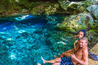 Muhteşem mavi turkuaz su ve kireçtaşı mağara çukurunda bikinili genç ve seksi kadın modeller Puerto Aventuras Quintana Roo Mexico 'da Tajma ha Tajmaha' yı sahneliyor..