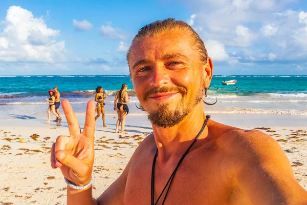 Mutlu model turist ve gezgin, Quintana Roo Mexico 'daki Turkuaz su insanları ve Tulum kulübeleriyle Karayip sahilleri ve sahil manzarasına gülümsüyor..