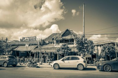 Tulum Meksika 02. Şubat 2022 Tipik renkli sokak yolu ve şehir manzarası boyunca araba trafiği palmiye ağaçları ve Meksika 'daki Tulum restoranlarının eski siyah beyaz resmi.