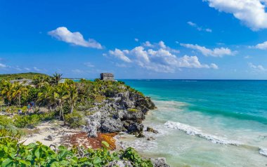Antik Tulum, Tulum Meksika 'daki tropikal doğal orman palmiyesi ve deniz manzarasında tapınak kalıntıları ve eserlerle Maya bölgesini harabeye çeviriyor..