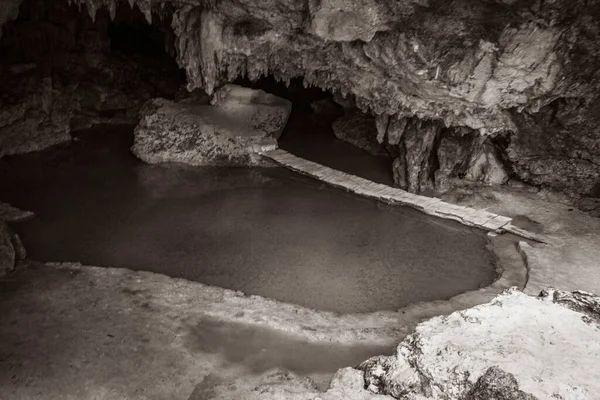 Old black and white picture of Amazing blue turquoise water and limestone cave sinkhole cenote at Santuario de los guerreros in Puerto Aventuras Quintana Roo Mexico.