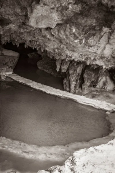 Old black and white picture of Amazing blue turquoise water and limestone cave sinkhole cenote at Santuario de los guerreros in Puerto Aventuras Quintana Roo Mexico.