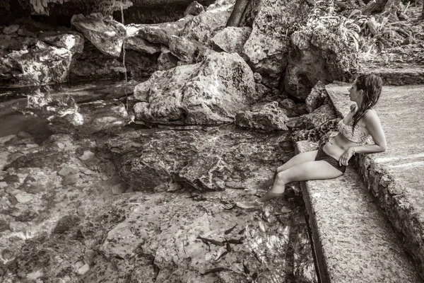 Old black and white picture of Sexy lady pretty woman model with bikini at amazing blue turquoise water and limestone cave sinkhole cenote Tajma ha Tajmaha in Puerto Aventuras Quintana Roo Mexico.