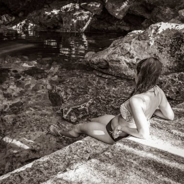 Old black and white picture of Sexy lady pretty woman model with bikini at amazing blue turquoise water and limestone cave sinkhole cenote Tajma ha Tajmaha in Puerto Aventuras Quintana Roo Mexico.