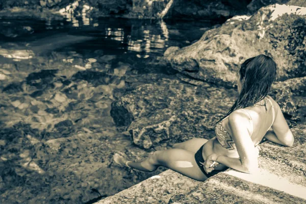 Old black and white picture of Sexy lady pretty woman model with bikini at amazing blue turquoise water and limestone cave sinkhole cenote Tajma ha Tajmaha in Puerto Aventuras Quintana Roo Mexico.