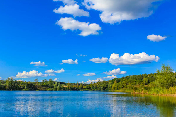 Beautiful quarry lake dredging pond lake with blue turquoise water blue sky and landscape nature forest panorama view in Eggestedt Schwanewede Osterholz Lower Saxony Germany.