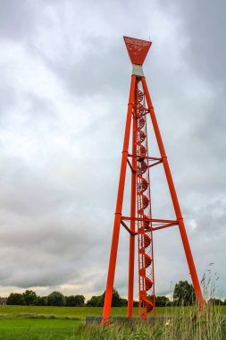 Endüstriyel vinçler ve güzel çayırları olan kırmızı kule deniz feneri Imsum Geestland Cuxhaven Aşağı Saksonya Almanya 'sında lezbiyen doğa deniz manzarası.
