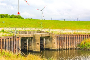 Endüstriyel vinçler ve güzel çayırları olan kırmızı kule deniz feneri Imsum Geestland Cuxhaven Aşağı Saksonya Almanya 'sında lezbiyen doğa deniz manzarası.