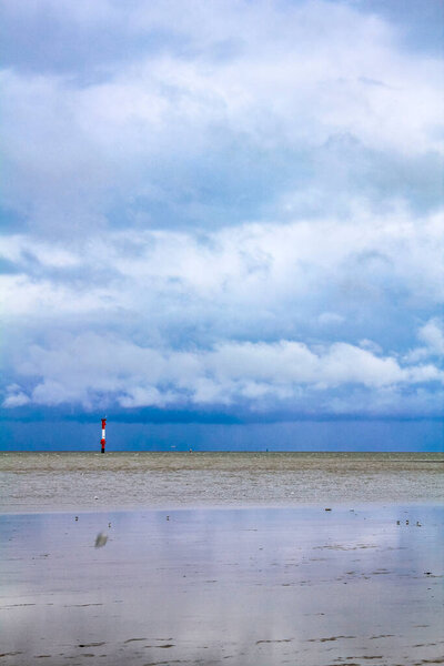 Industrial area cranes and red tower lighthouse with beautiful grassland and dike dyke nature seascape panorama in Imsum Geestland Cuxhaven Lower Saxony Germany.
