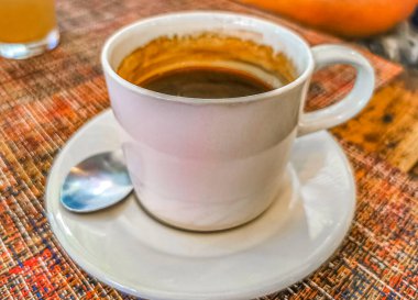 Glass cup of americano black coffee with spoon and plate on table food and drink in the restaurant PapaCharly Papa Charly in Playa del Carmen Quintana Roo Mexico.