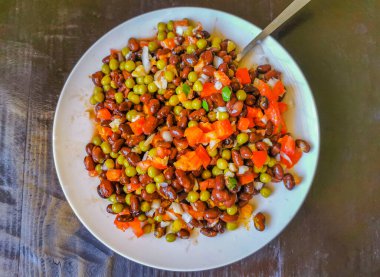Vegetable dish soup with beans peas potatoes onions tomato and garlic on a white plate bowl with fork or spoon in Mexico.