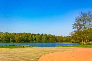 Natural beautiful panorama view with lake river walking pathway and green plants trees in the forest of Speckenbuetteler Park in Lehe Bremerhaven Germany.
