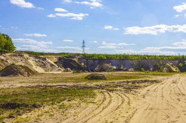 Excavated sand mountains and rubble piles quarry lake dredging pond lake with blue sky and landscape nature forest panorama view in Eggestedt Schwanewede Osterholz Lower Saxony Germany.