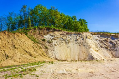 Excavated sand mountains and rubble piles quarry lake dredging pond lake with blue sky and landscape nature forest panorama view in Eggestedt Schwanewede Osterholz Lower Saxony Germany.