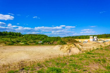 Excavated sand mountains and rubble piles quarry lake dredging pond lake with blue sky and landscape nature forest panorama view in Eggestedt Schwanewede Osterholz Lower Saxony Germany.